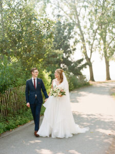 a bride and groom walking and looking at each other at their navy and burgundy wedding in seattle at the edgewater hotel.