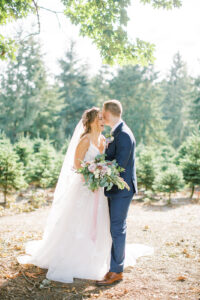 a bride laughing at her groom who is standing in front of her surrounded by christmas trees at trinity tree farm wedding venue