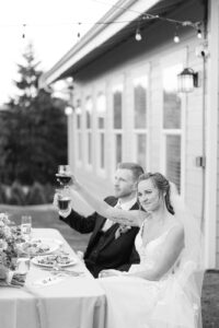 a black and white photo of a couple toasting at their wedding at trinity tree farm in issaquah