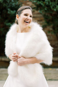 a bride in a fur shawl looking away from the camera and laughing