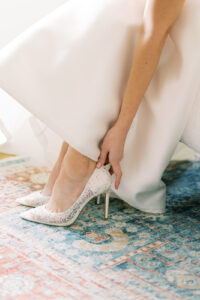 a bride in her wedding dress putting on her shoes