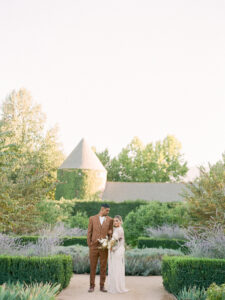 a bride and groom standing in a vineyard at their wedding in southern california