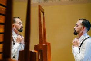 a man getting read for his wedding in the mirror