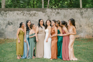 a handful of bridesmaids in colorful dresses standing next to the bride at her mexico elopement