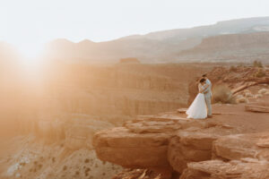 a bride and groom standing on the cliffs of utah's red rocks for an elopement in utah