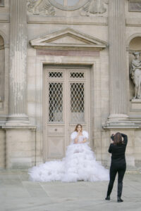 a paris photographer taking a picture of a woman in a big fluffy pink dress at the louvre