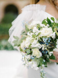 a wedding bouquet with white andgreen and little pops of blue colors