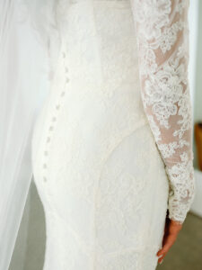 a close up of a white laced wedding dress with lace sleeves