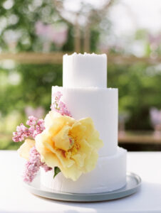 white wedding cake with a large yellow flower and some lavender sprigs