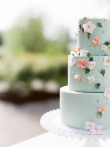 a light blue wedding cake with small colorful flowers on it