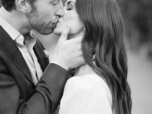 a black and white photo of a man and woman kissing for their engagement session in aspen