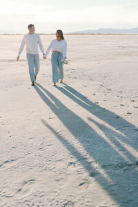 a couple holding hands and running towards the camera saltair engagement at sunset