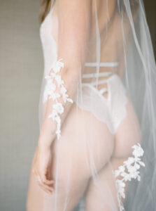 a photo of a woman's butt and back in white lingerie and a lacy veil covering her at her bridal boudoir session in seattle