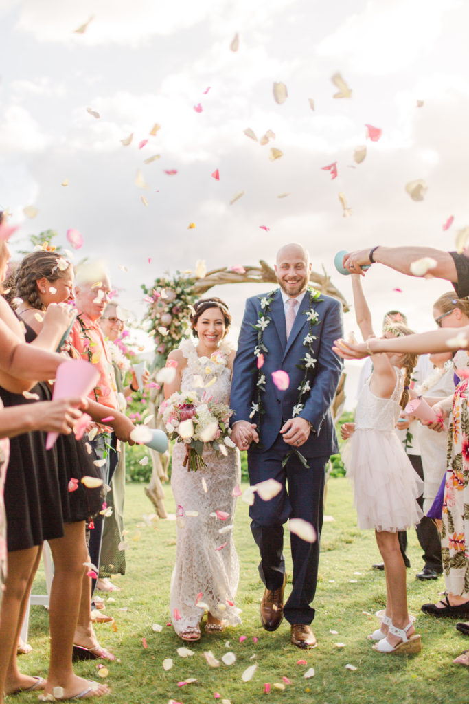 bride and groom in Maui walking while guests throw petals to celebrate