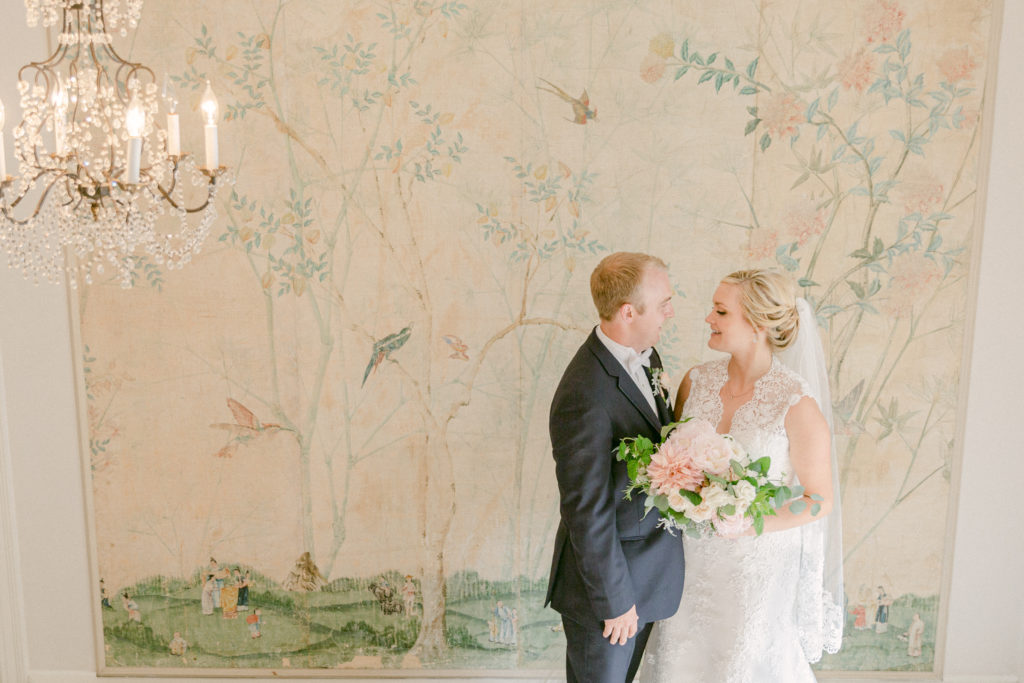 bride and groom standing inside Lakewold Gardens in front of an old large mural on the wall