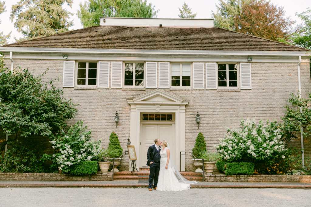 bride and groom kissing in front of Lakewold Gardens wedding venue
