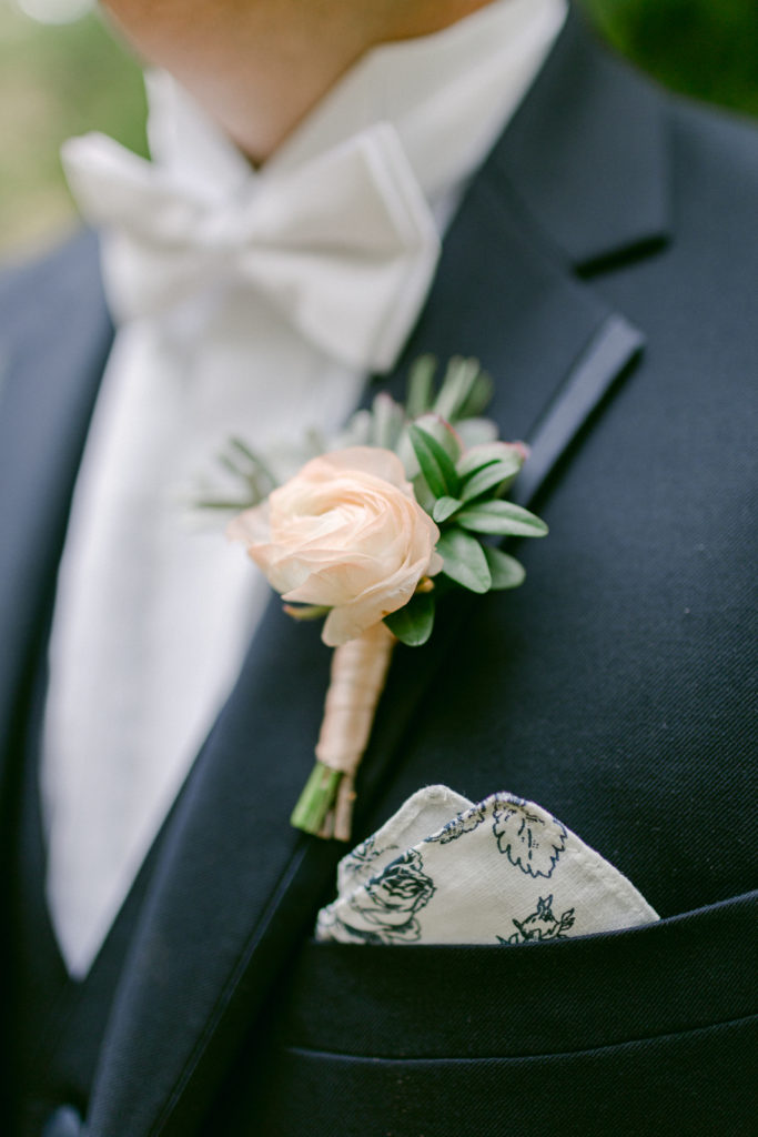 wedding boutonnière on a grooms navy suit with patterned pocket square and bowtie