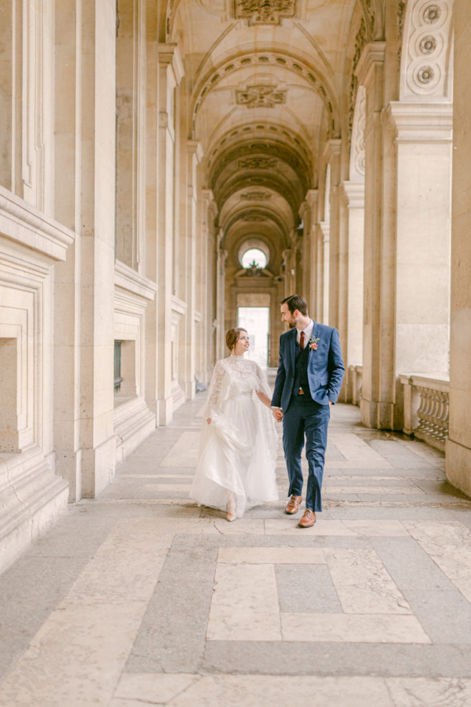 bride and groom holding hands and walking near the louvre in paris france