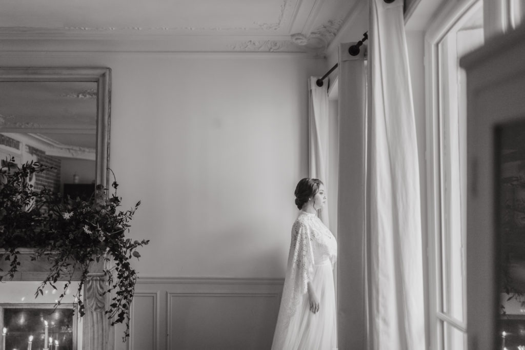 black and white photos of a bride looking out the window in a paris apartment