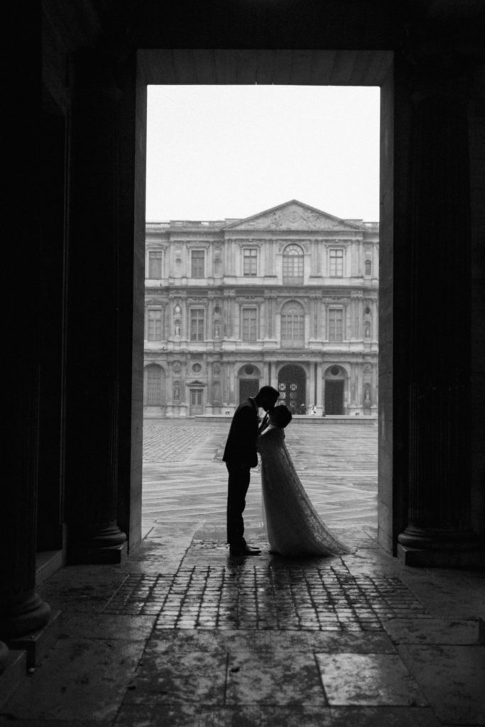 silhouette of bride and groom kissing in a alleyway near the Louvre in Paris