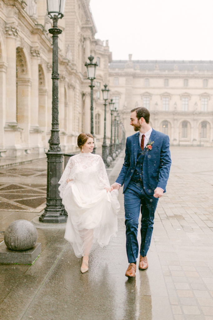 bride and groom walking near the Louvre in Paris with street lamps on the left side