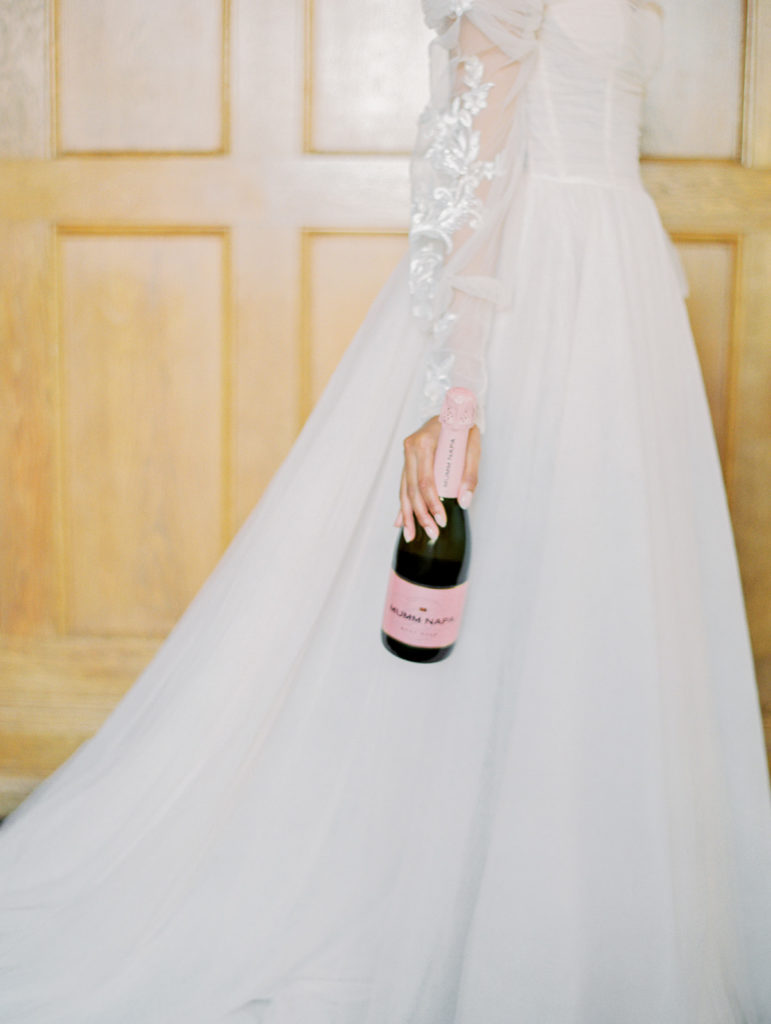 woman in pink wedding dress holding pink champagne bottle
