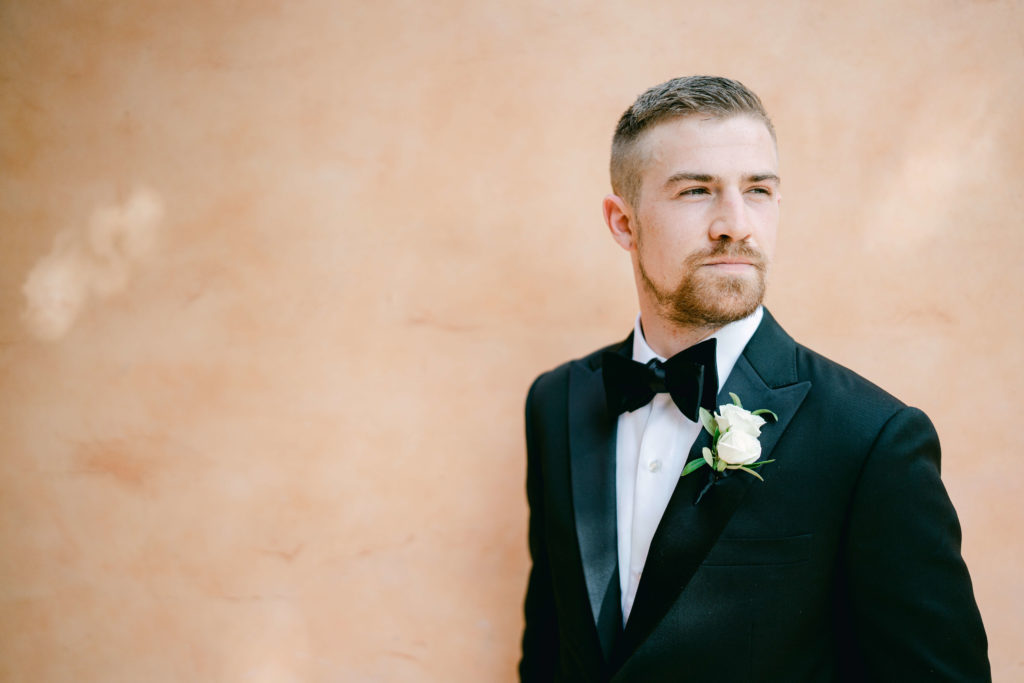 groom in a black suit looking away from the camera