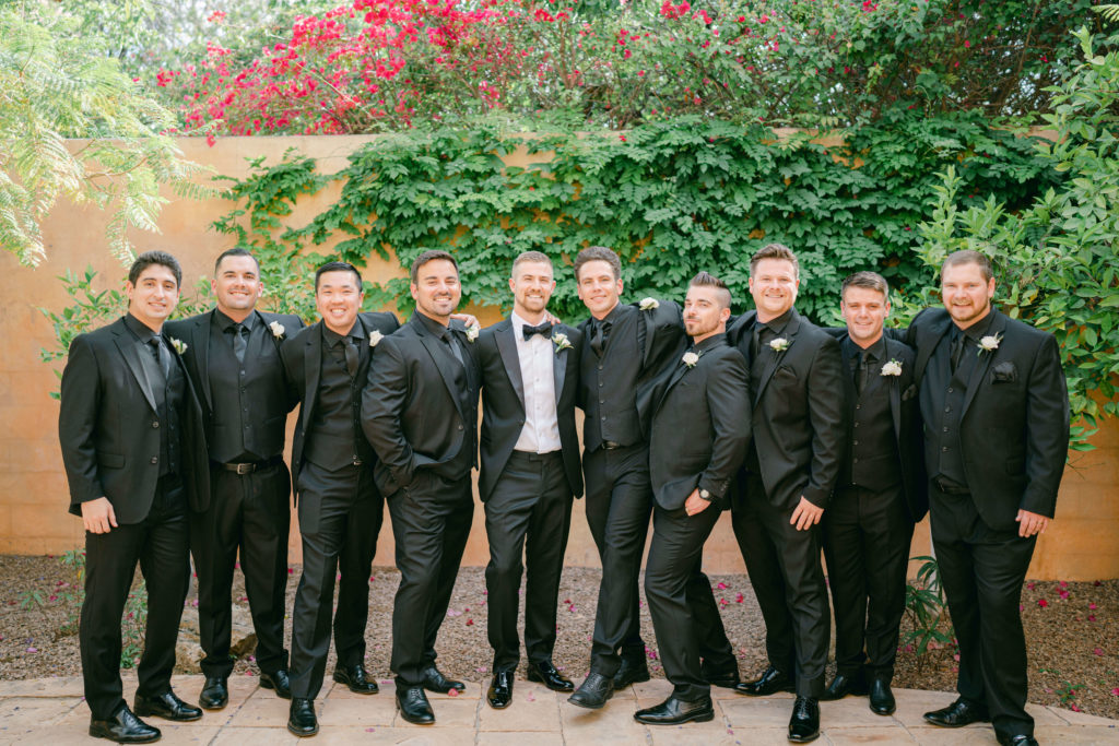 groom and groomsmen standing in front of an ivy wall