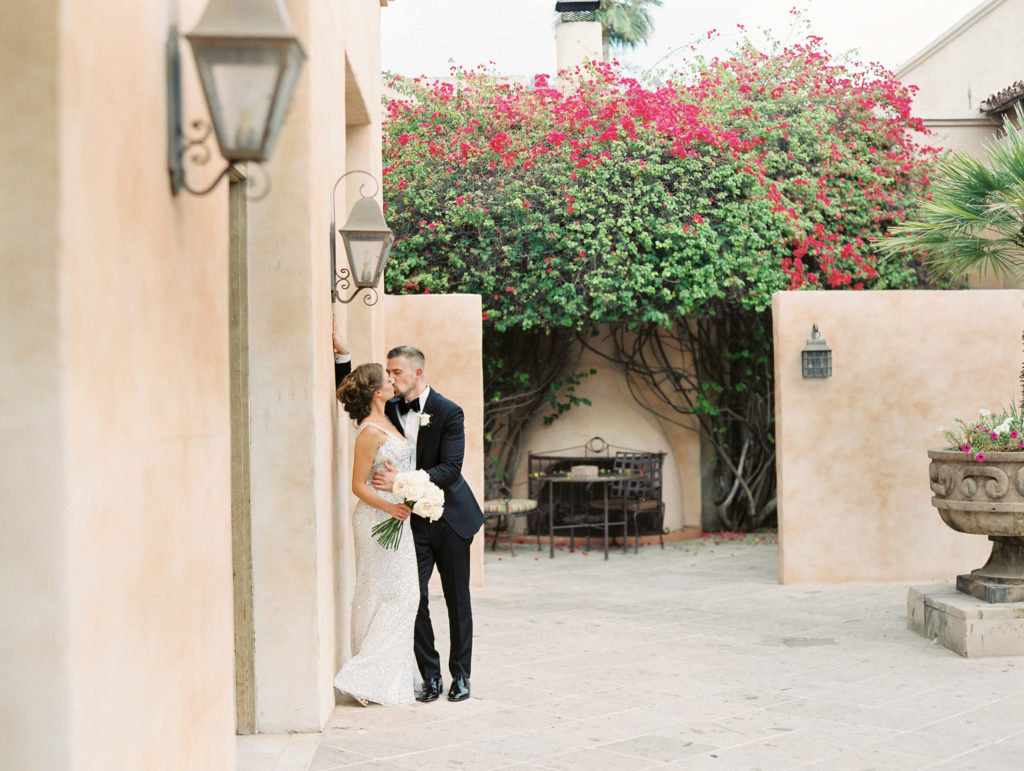 bride being kissed by the groom up against a wall under a light fixture at royal palms resort in phoenix