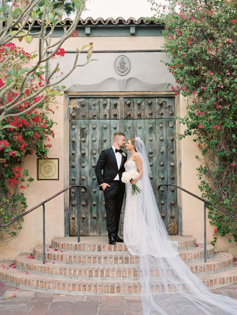 bride and groom looking into each others eyes and standing in front of big rustic doors at the royal palms resort