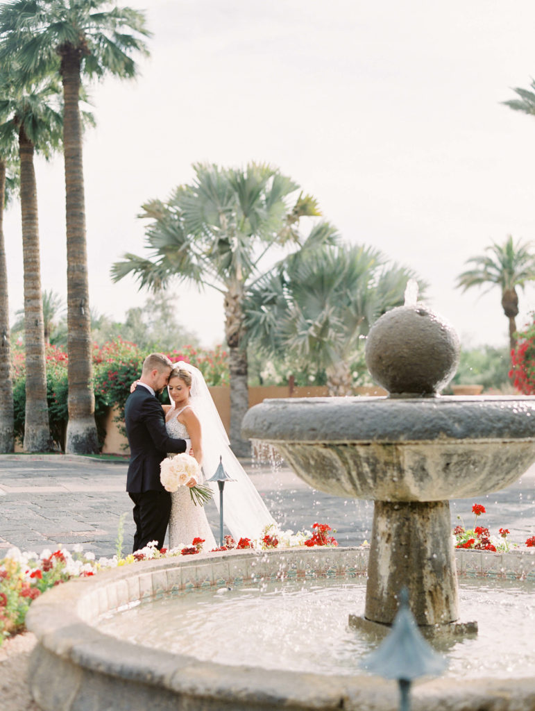 bride and groom facing each other standing in front of the water fountain at the royal palms resort