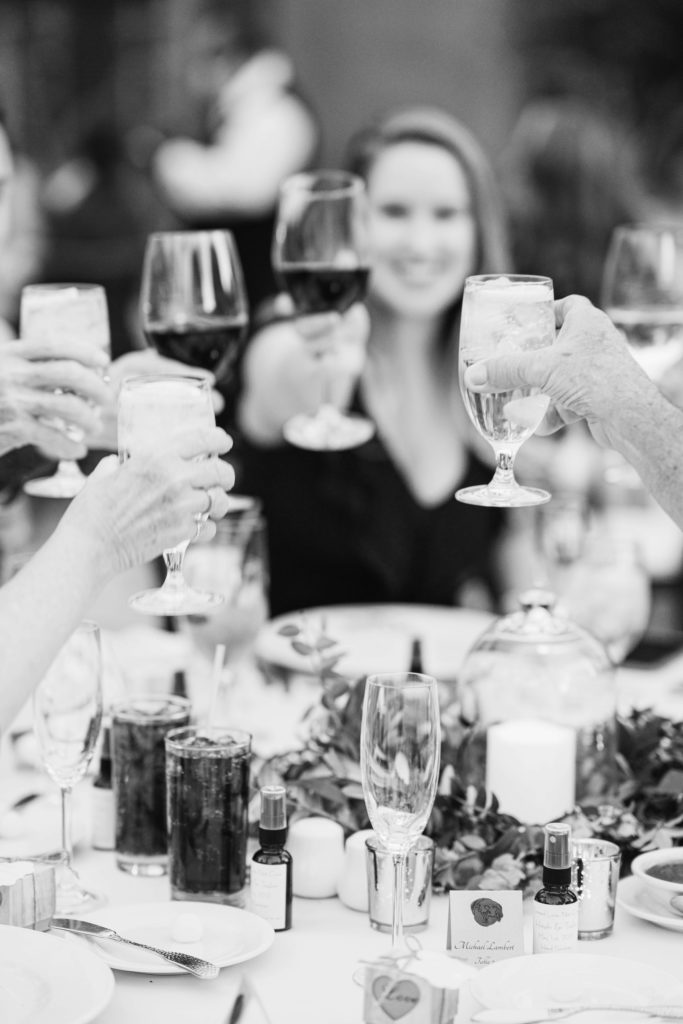 black and white photo of guests toasting with their glasses 