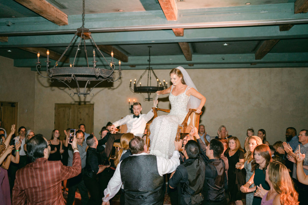 bride and groom on chairs during their horah dance at their wedding reception