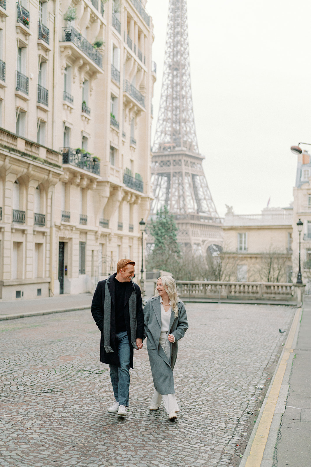 a couple walking the streets of paris holding hands with the eiffel tower in the background