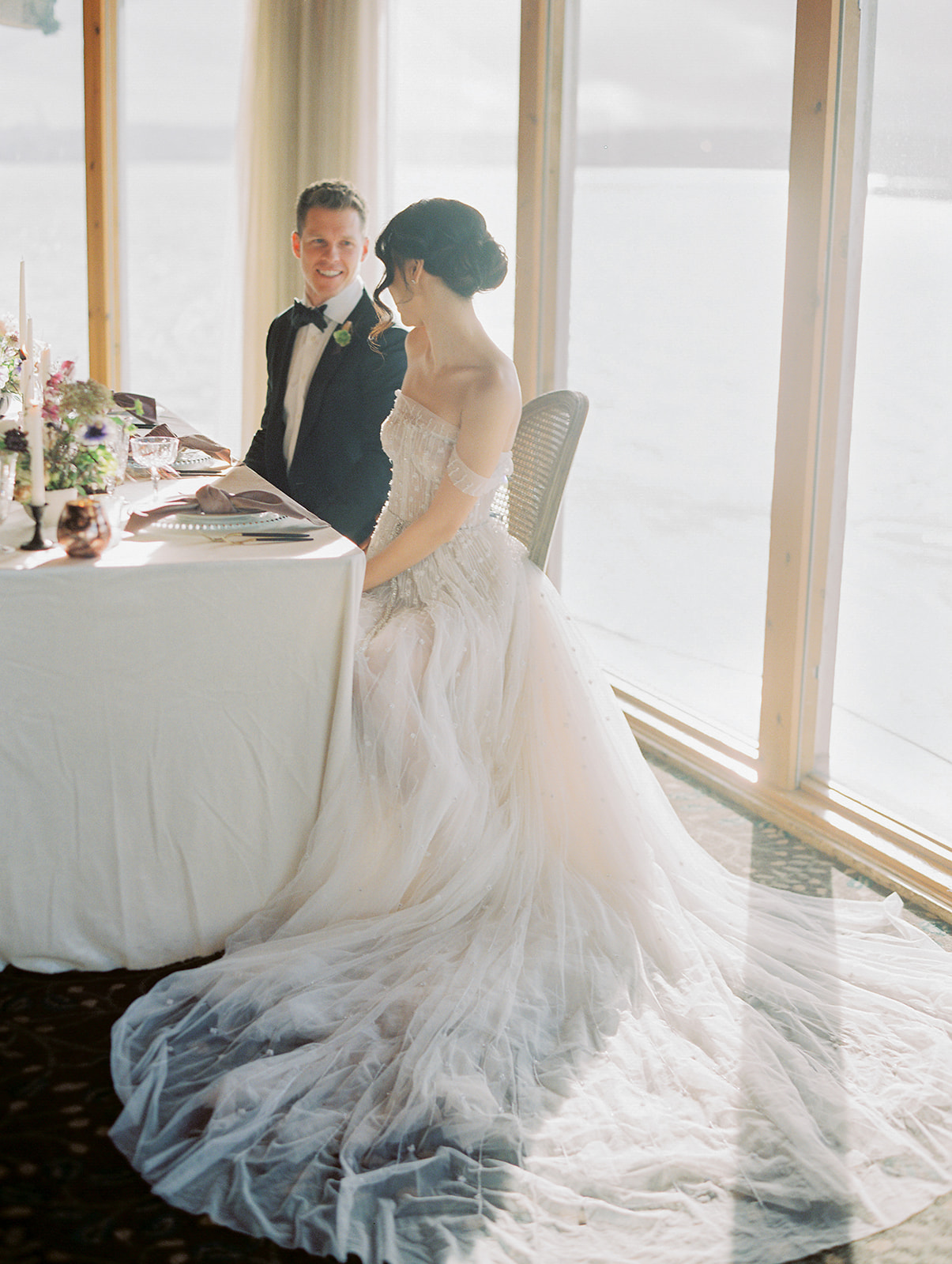 a bride and groom sitting down at their wedding table at the edgewater hotel
