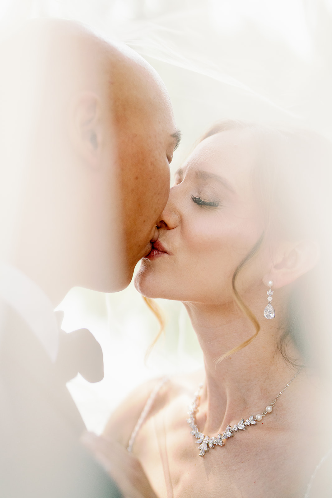 a bride and groom kissing under a veil for their gray bridge wedding