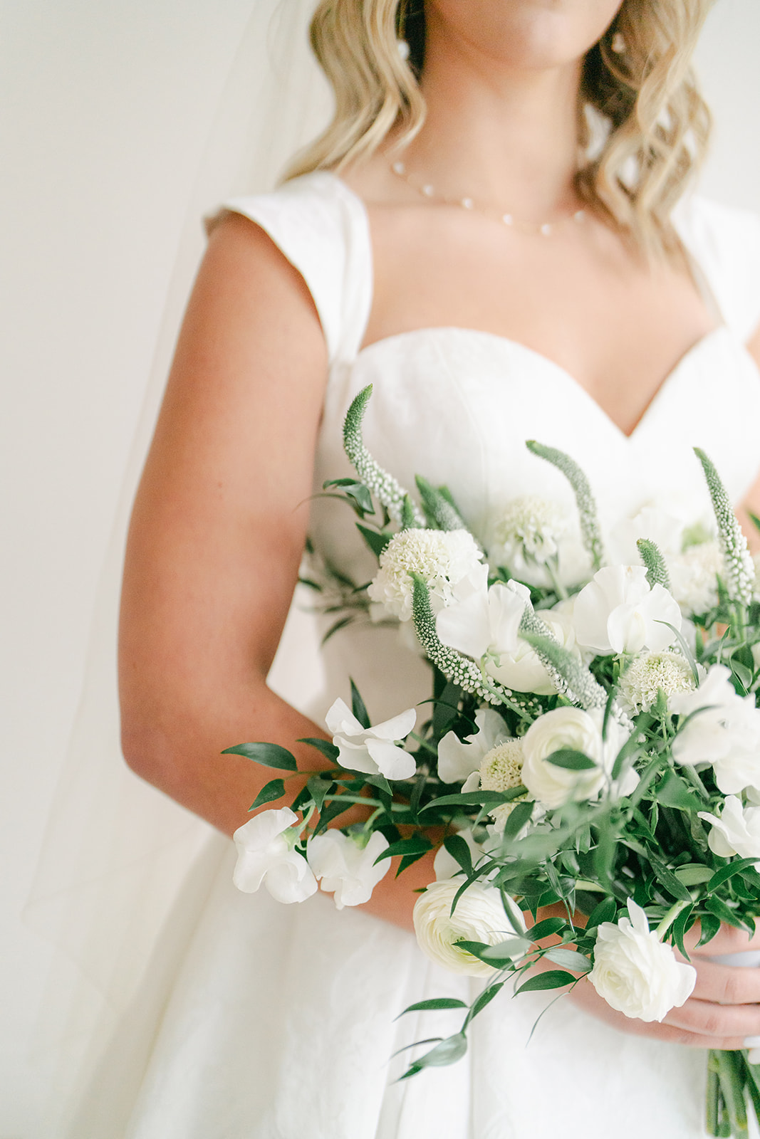 a woman in a wedding dress holding her white and green wedding bouquet