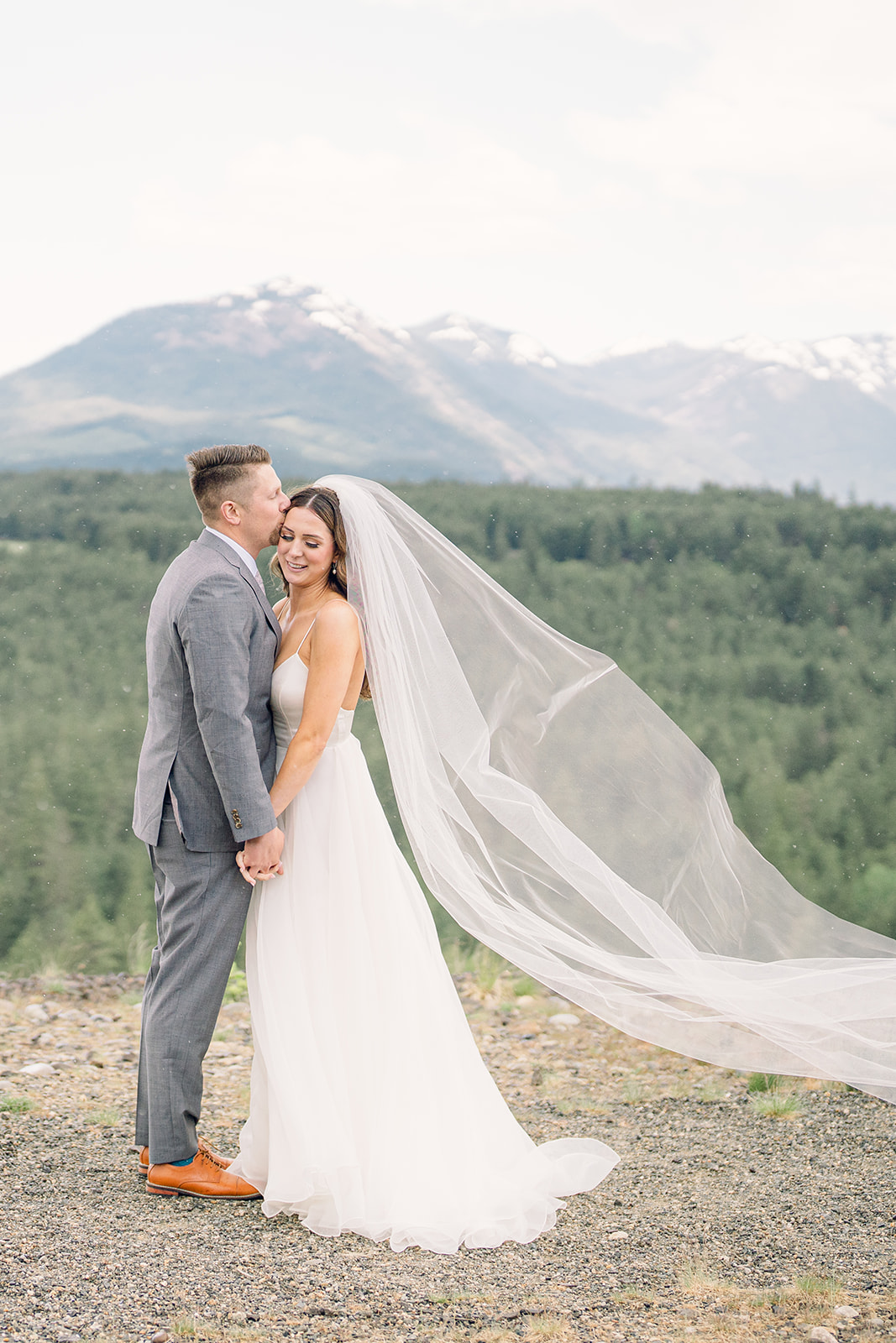 a groom kissing the side of his bride's temple overlooking mountains at their swiftwater cellars wedding