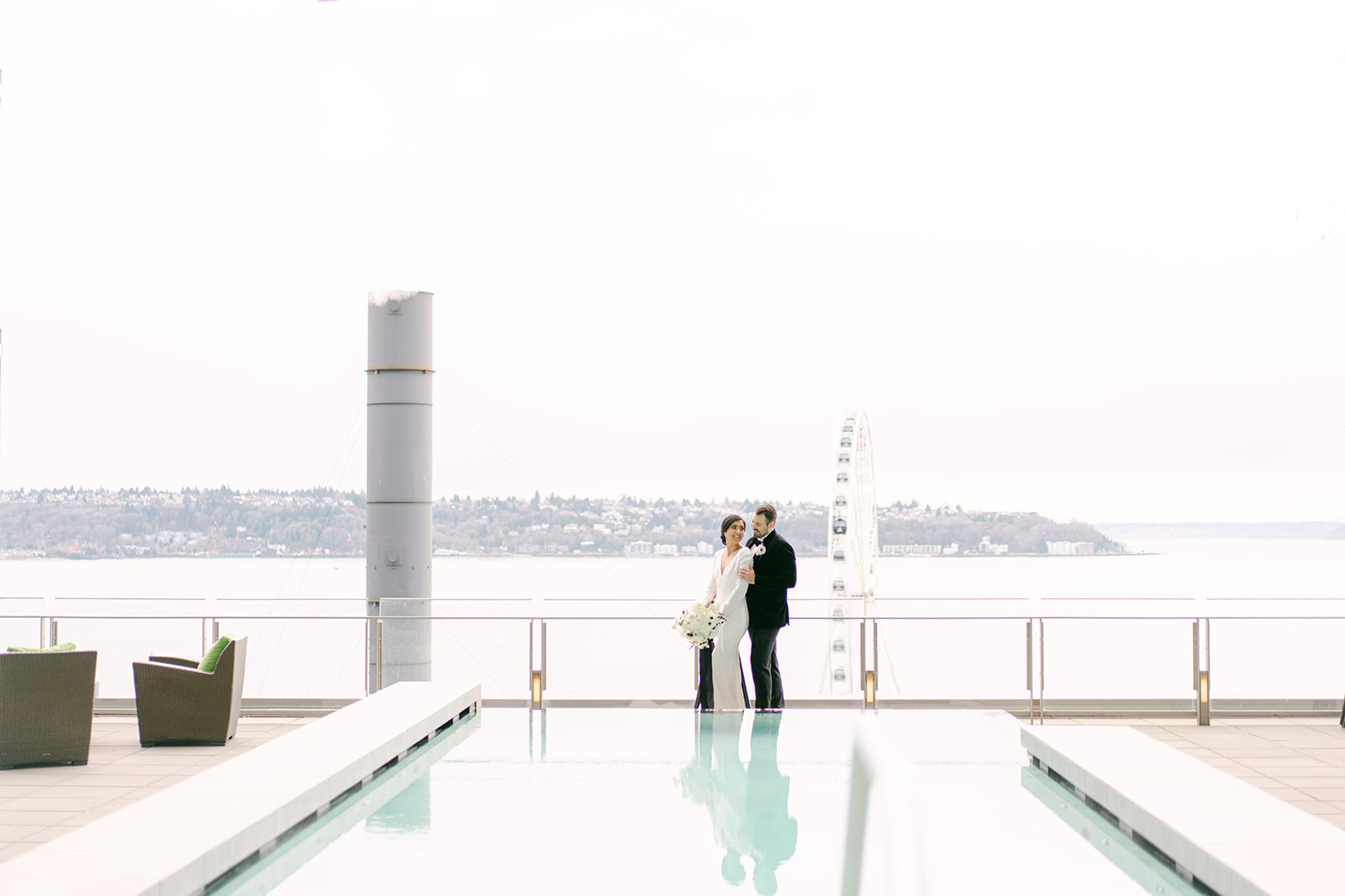 a bride and groom standing near a pool on the roof of this four seasons wedding in seattle