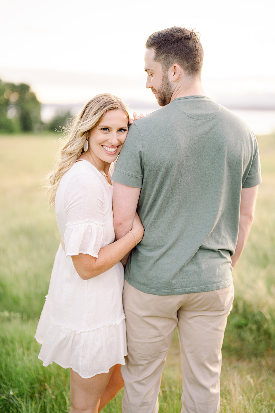 a woman holding on to a mans arm and smiling at the camera for their engagement session locations near seattle
