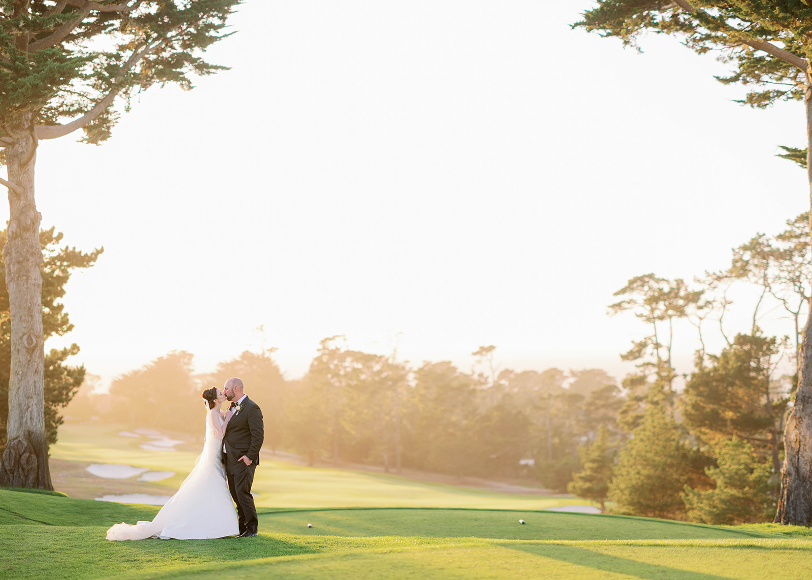 a bride and groom kissing at their Monterey wedding venue during sunset