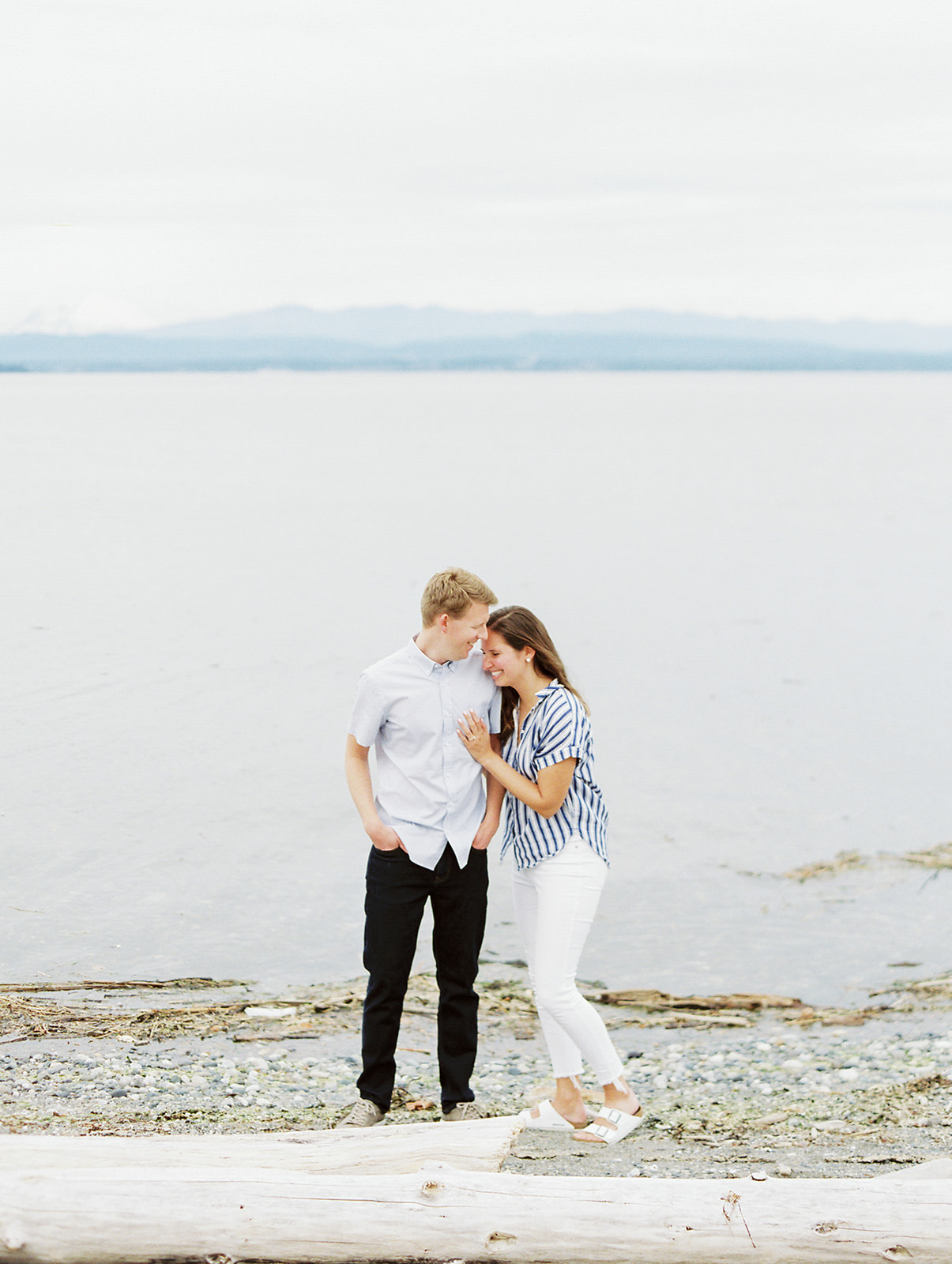 a man and woman on a beach for their seattle engagement photoshoot