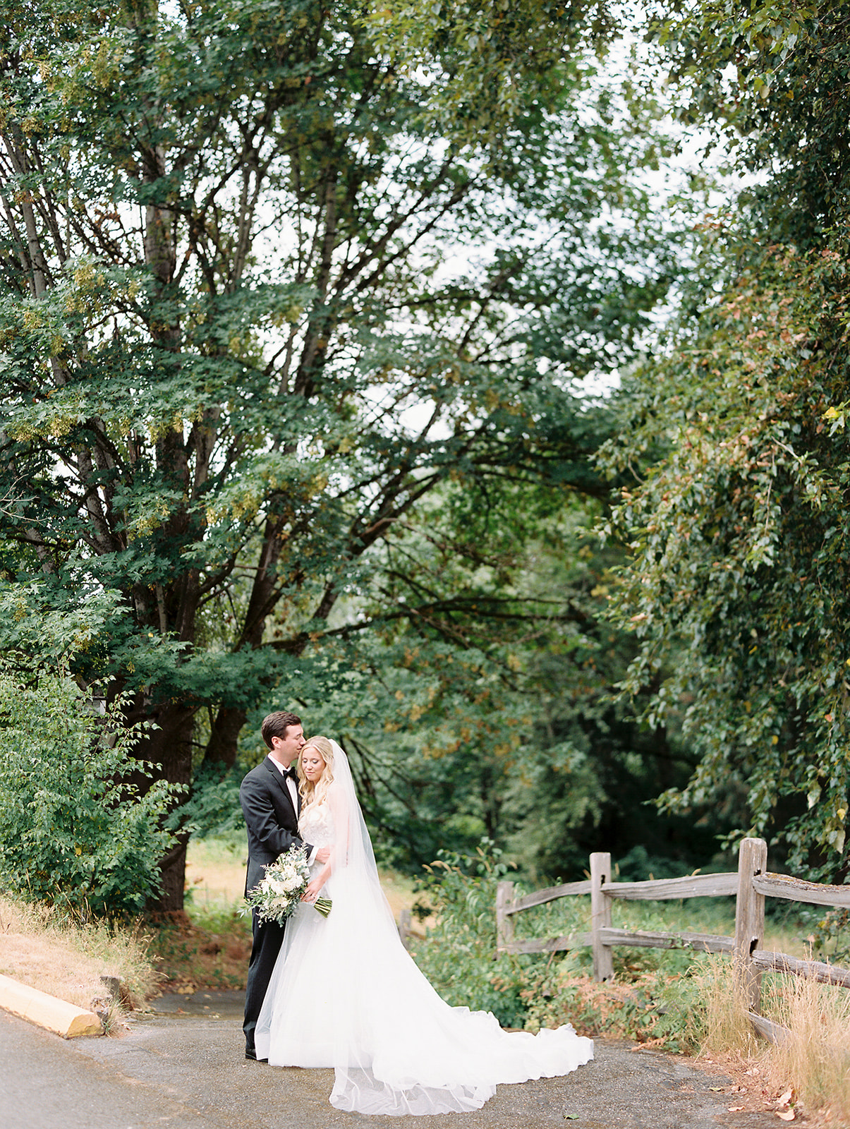 a bride and groom standing near some trees and embracing each other at their wedding at columbia collective wedding