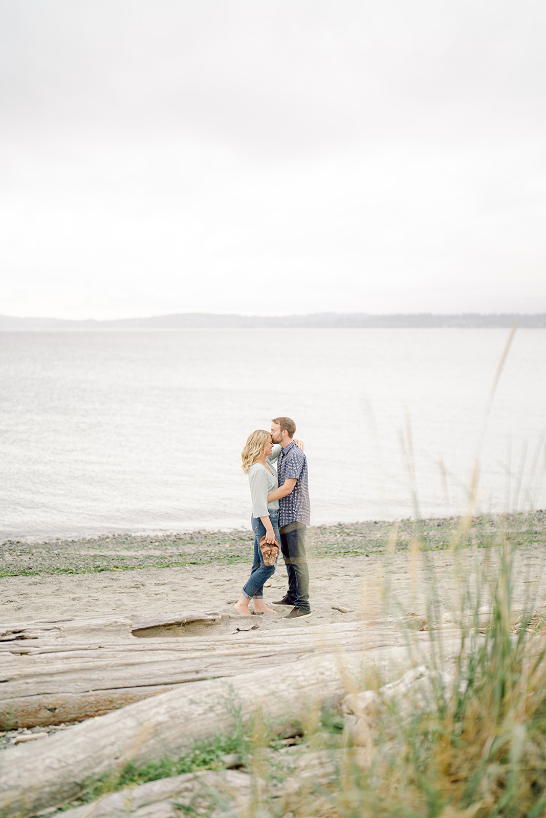 a couple kissing on the beach at discovery park by a seattle engagement photographer