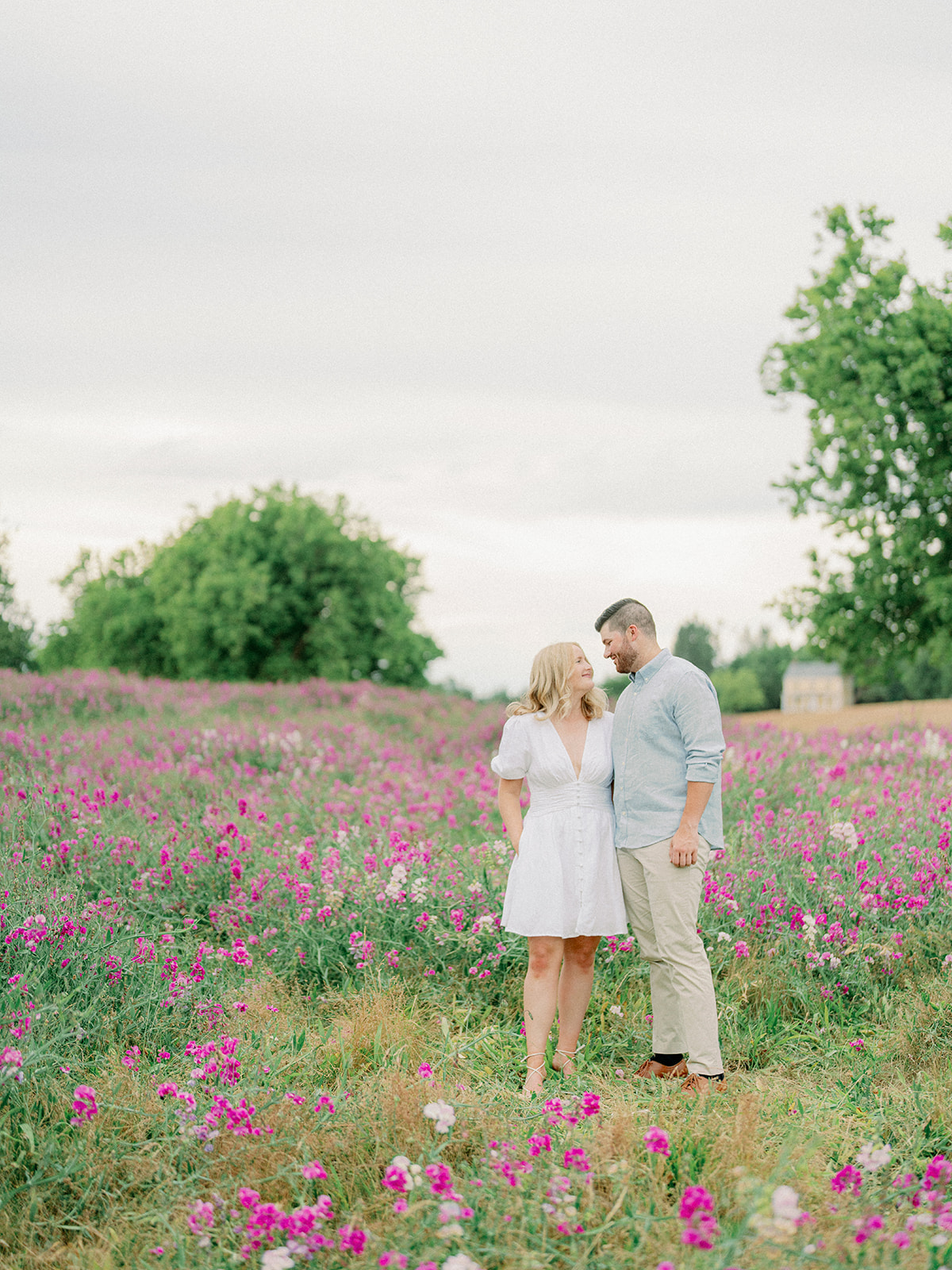 a couple in a field of wild sweet peas standing together at their discovery park engagement session