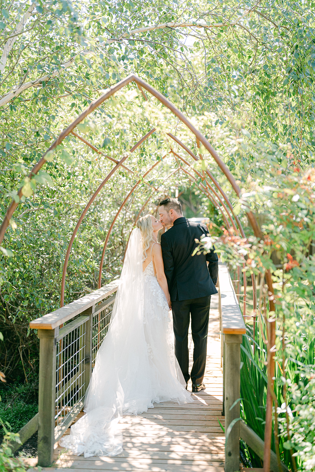a bride and groom walking away from the camera and kissing at their san juan island wedding venue at outlook inn