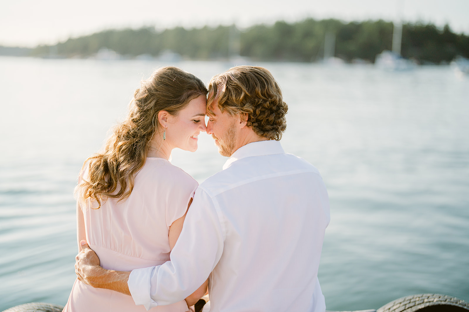 a couple sitting on the dock at this roche harbor engagement during sunset