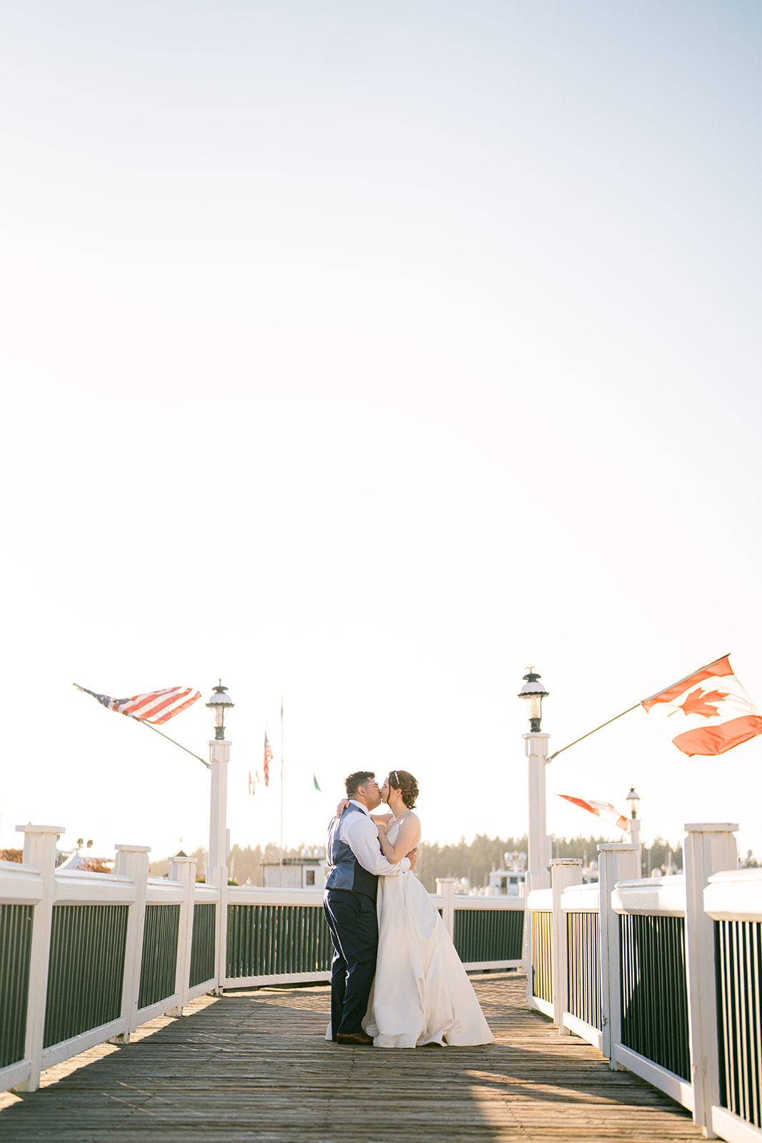 a couple standing on a dock at their micro wedding at roche harbor resort during sunset