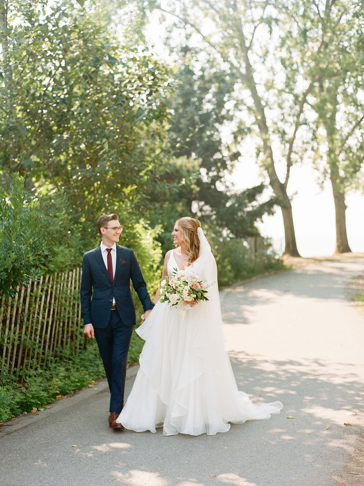 a bride and groom walking and looking at each other at their navy and burgundy wedding in seattle at the edgewater hotel.