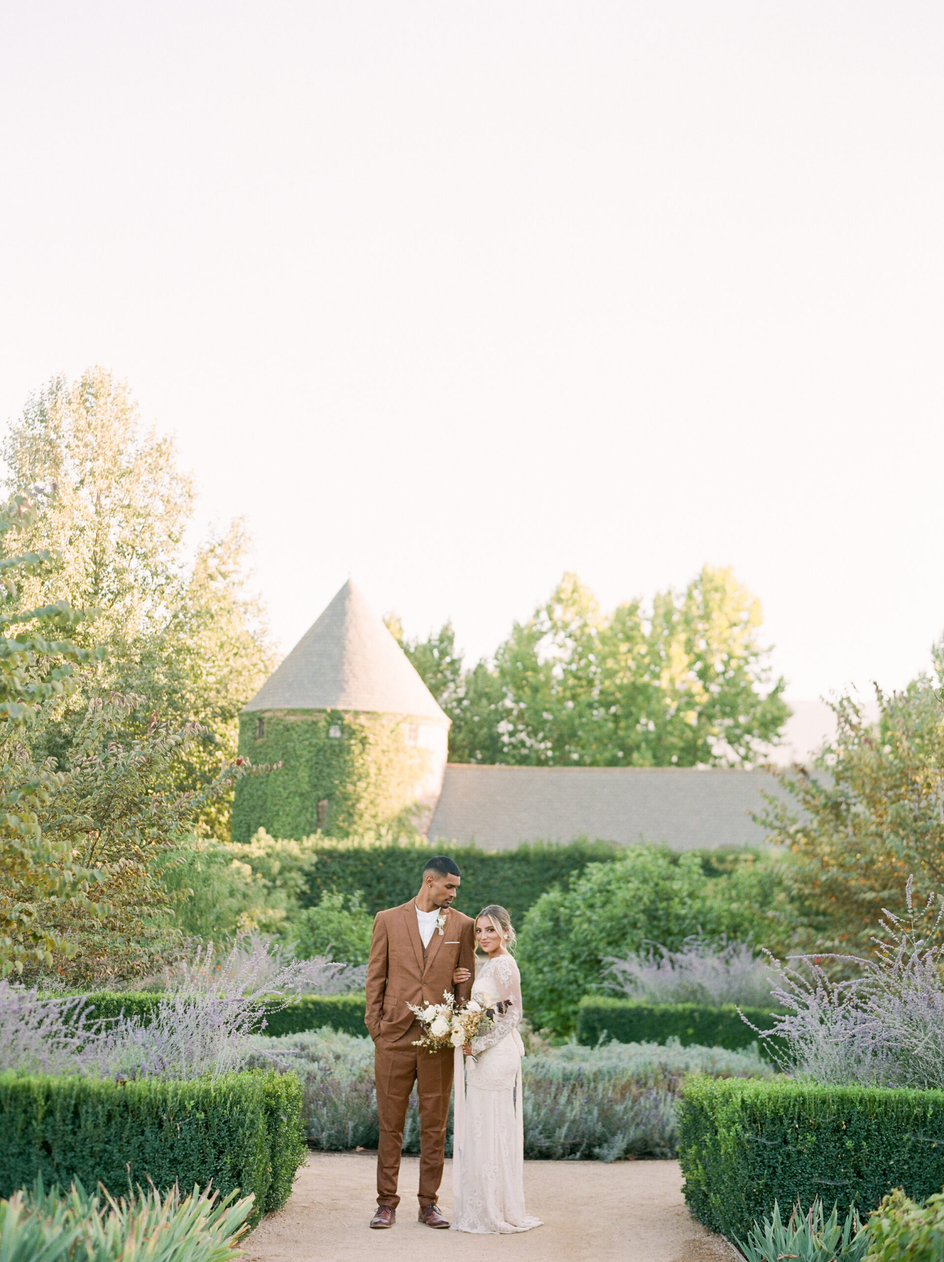 a bride and groom standing in a vineyard at their wedding in southern california